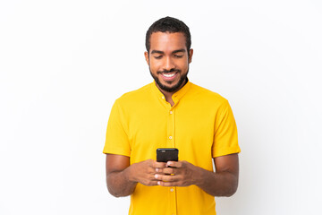 Young Ecuadorian man isolated on white background sending a message with the mobile
