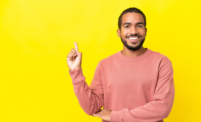 Naklejka premium Young latin man isolated on yellow background happy and pointing up