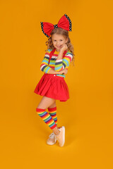 beautiful happy blonde girl with a red bow on her head in a red skirt, a colored blouse with colored socks on a yellow background