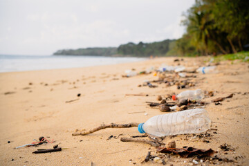 Trash bottles dumped on the sandy beach during the monsoon sea.