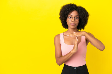 Fototapeta na wymiar Young African American woman isolated on yellow background making time out gesture