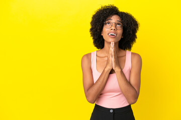 Young African American woman isolated on yellow background keeps palm together. Person asks for something