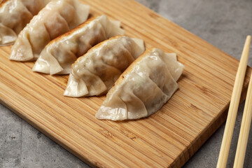 Fototapeta na wymiar Gyoza or dumplings snack with soy sauce on wood board and grey clay background