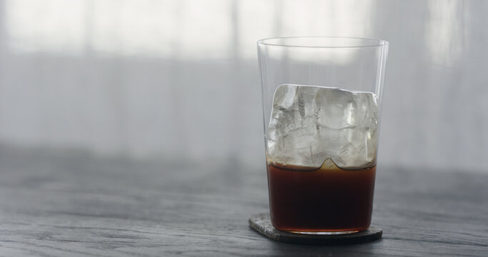 Coffee Pour Over Ice Cube In Tumbler Glass On Black Wood Table