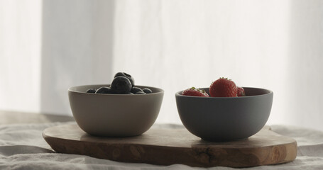 strawberries and blueberries in bowls on wood table