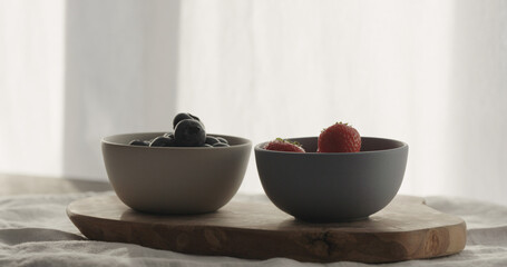 strawberries and blueberries in bowls on wood table