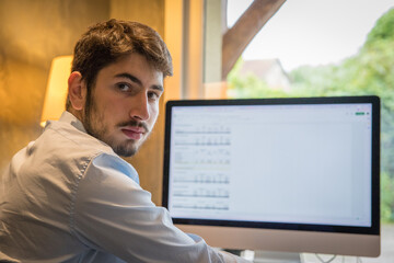 portrait d'un jeune homme employé en train de travailler assis devant son ordinateur, ou bien en...