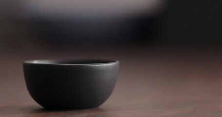 Black empty ceramic bowl on walnut table