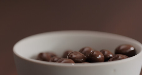 chocolate covered pistachios in white bowl on walnut table