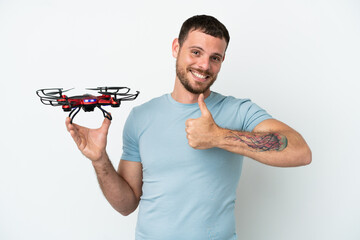 Young Brazilian man holding a drone isolated on white background giving a thumbs up gesture