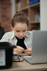 Boy using a laptop to program assembled robot from plastic bricks. STEM Education for kids.