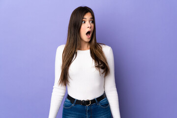 Teenager Brazilian girl over isolated purple background doing surprise gesture while looking to the side