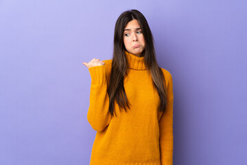Teenager Brazilian girl over isolated purple background unhappy and pointing to the side