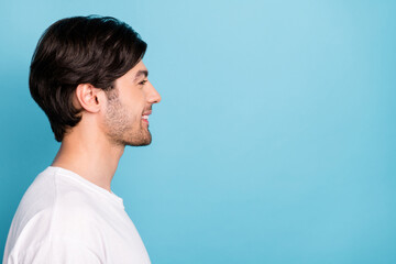 Profile photo of funny young guy look empty space wear white t-shirt isolated on blue color background