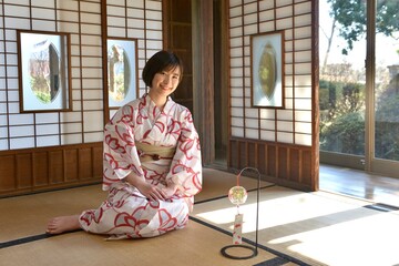古民家の和室に座り微笑む浴衣を着た若い女性