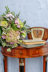 antique sideboard with flowers, old clock and old books