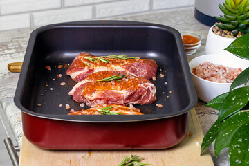 Raw marbled beef steak slices with salt and spices on metal baking dish for oven background. The preparation of a fresh meat for dinner.