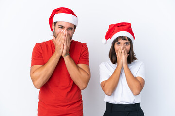 Young couple with christmas hat isolated on white background smiling a lot while covering mouth