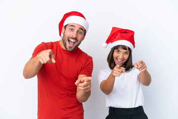 Young couple with christmas hat isolated on white background points finger at you while smiling