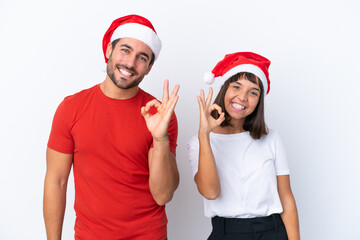 Young couple with christmas hat isolated on white background showing an ok sign with fingers