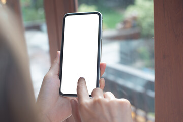 Cell phone mockup image blank white screen.  Woman hand holding, using mobile phone at coffee shop.