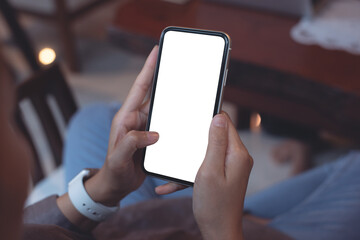 Cell phone mockup image blank white screen.  Woman hand holding, using mobile phone in coffee shop, close up