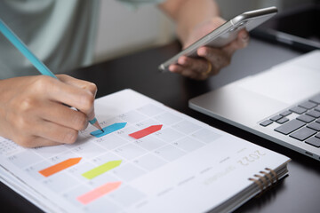 Event planner timetable agenda plan on year 2022 schedule event. Business woman checking planner on mobile phone, taking note on calendar desk on office table - obrazy, fototapety, plakaty