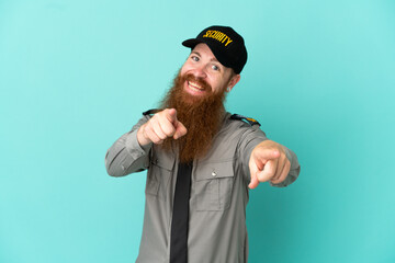 Redhead security man isolated on white background points finger at you while smiling