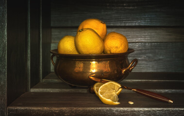 ripe lemons lie on a wooden shelf in copper dishes. © Mykhailo
