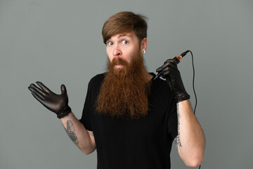 Tattoo artist redhead man isolated on blue background having doubts while raising hands