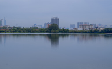 Fototapeta na wymiar Beautiful city scape view of Kuala Lumpur city from the Kepong through the lake. Sunny day scene, reflecting on water and high buildings in background. 