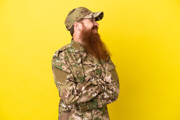 Fototapeta premium Military Redhead man over isolated on yellow background looking side