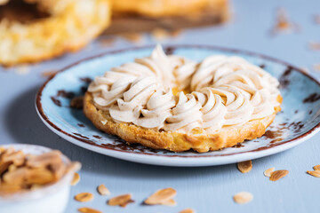 Dessert called Paris Brest on a grey background with powder sugar and almond leaves and almond creme between - obrazy, fototapety, plakaty