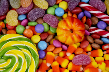 Fototapeta na wymiar Mixed halloween candy background close-up top view stock images. Halloween sweet lollipop, pumpkin, candy corn detail stock photo. Different types of candies images