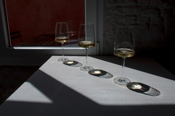 Composition of glasses filled with white wine and shadows