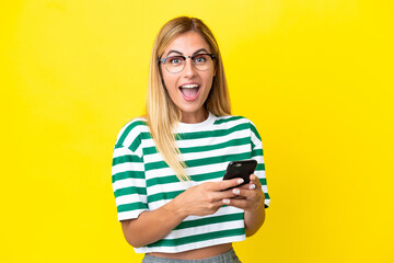 Fototapeta premium Blonde Uruguayan girl isolated on yellow background surprised and sending a message