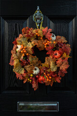 Thanksgiving wreath for front door. Closeup fall harvest wreath with pumpkins, maple leaf and berry...