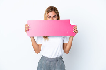 Blonde Uruguayan girl isolated on white background holding an empty placard and hiding behind it