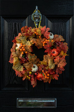 Thanksgiving wreath for front door. Closeup fall harvest wreath with pumpkins, maple leaf and berry for Halloween. Outdoor home decor