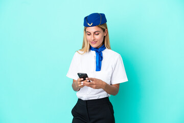 Airplane stewardess Uruguayan woman isolated on blue background sending a message with the mobile