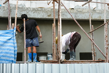 two worker team stand on wooden scaffolding install use for high level.  concrete wall plaster...