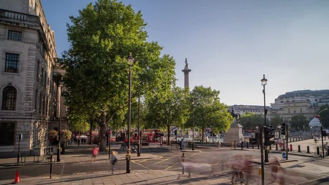 Trafalgar Square in London, England, time lapse with zoom in. Junction by Trafalgar Square with speeded up people and traffic. Zooms in.