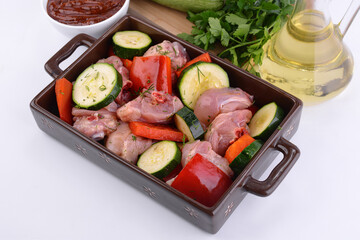 raw chicken with vegetables in a baking dish 