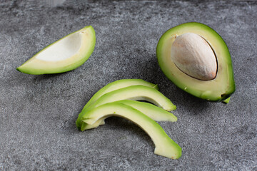 green avocado lie on an artificial stone board. diet food. green vegetable.