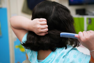 Fototapeta premium Asian girl combing her hair Taken from the back