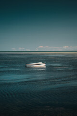 Small cute white fishing boat with minimal blue and turquoise ocean background. Minimal and calm...