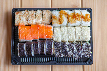 Making sushi and rolls at home. Sushi with seafood, salad and white rice. Food for family and friends. A set of different rolls and sushi on a tray.