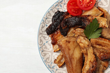 Tasty fried pork lard with parsley and tomatoes on white wooden table, top view