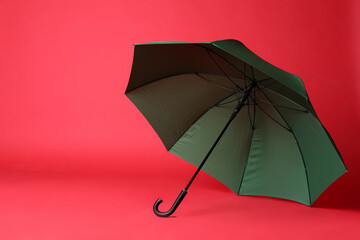 Stylish open green umbrella on red background. Space for text