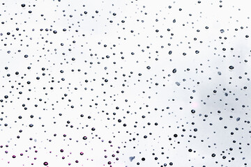 Blurred image of water droplets on the windshield of the car after the rainstorm has passed gives a feeling of loneliness. A large amount of raindrops settled on the windshield of the car.